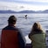 3 people witnessing a whale’s fluke poking out of the water
